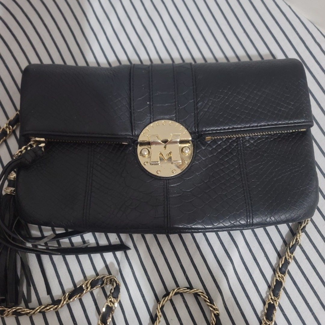 METROCITY Black Leather Embossed Chain Strap Clutch Bag (Category: Luxury Bags & Wallets) located in Pasig City. Submitted by bunny.bella (Listing ID 1455310152, Image 1). Description: Chic black leather Metrocity with gold logo. Zip closure, detachable chain strap. Perfect for essentials. Very good condition Genuine leather.