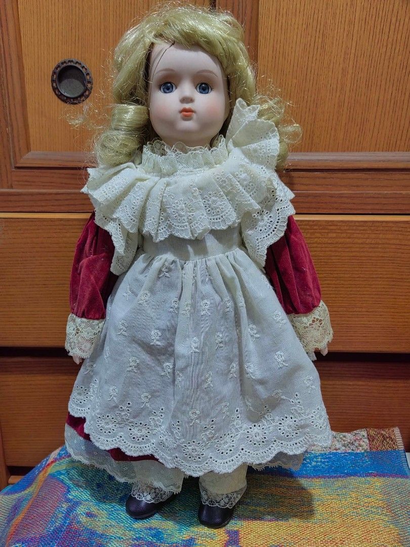 Porcelain Doll (Category: Figurines & Statues) located in Cebu City. Submitted by dudes_villanueva (Listing ID 1455226994, Image 1). Description: Porcelain Doll 📌 features a Victorian-style layered lace dress with red velvet sleeves and blonde curly hair. 📌 Crafted with a bisque porcelain head, hands, and lower limbs, paired with a soft body and detailed fabric costuming. 📌Styled with traditional painted facial features, fixed blue glass-like 