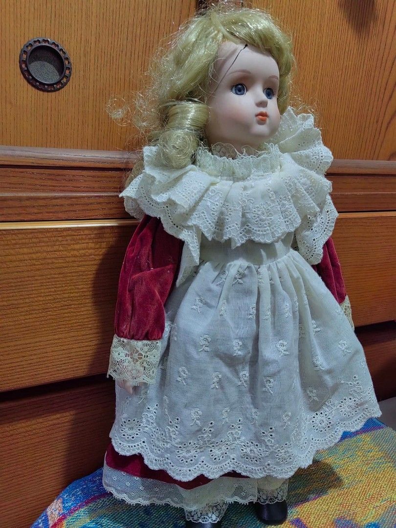 Porcelain Doll (Category: Figurines & Statues) located in Cebu City. Submitted by dudes_villanueva (Listing ID 1455226994, Image 3). Description: Porcelain Doll 📌 features a Victorian-style layered lace dress with red velvet sleeves and blonde curly hair. 📌 Crafted with a bisque porcelain head, hands, and lower limbs, paired with a soft body and detailed fabric costuming. 📌Styled with traditional painted facial features, fixed blue glass-like 