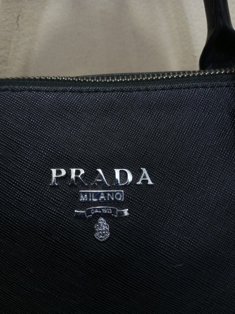 Prada Saffiano Leather Briefcase Milano (Category: Luxury Bags & Wallets) located in Bacolod City. Submitted by exequelgra46775 (Listing ID 1455230189, Image 2). Description: - Prada Saffiano leather briefcase - Classic black color - Secure zip closure with a small padlock included - Features high-quality YKK zippers - Interior lined with distinctive green fabric - Ideal for professional use or travel.