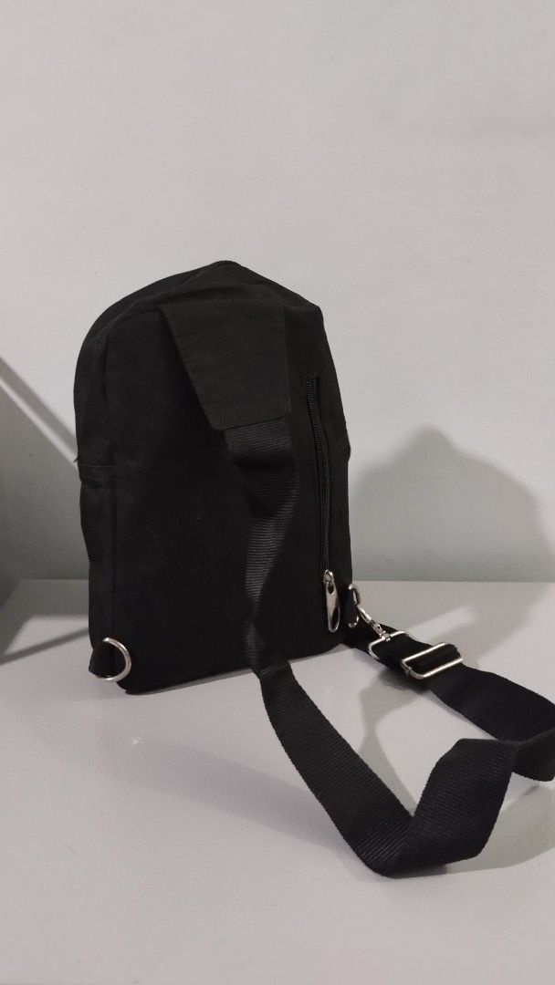 Black Canvas Crossbody Bag with Reflective Stripes (Category: Sling Bags) located in Taguig. Submitted by pricedropph (Listing ID 1455451578, Image 2). Description: Black canvas sling bag. Has two reflective stripes across the front. A small diamond-shaped patch with two vertical lines is on the upper front. A logo patch is on the lower front. Zipper closure. Adjustable strap..