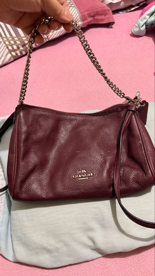 Coach Carrie Crossbody Clutch (Category: Luxury Bags & Wallets) located in Bacoor. Submitted by reich23 (Listing ID 1455462876, Image 1). Description: Crafted from durable pebbled leather in a rich burgundy/oxblood shade, featuring a silver-tone chain short handle, a raised Coach metallic logo, and a detachable longer leather strap for crossbody styling..