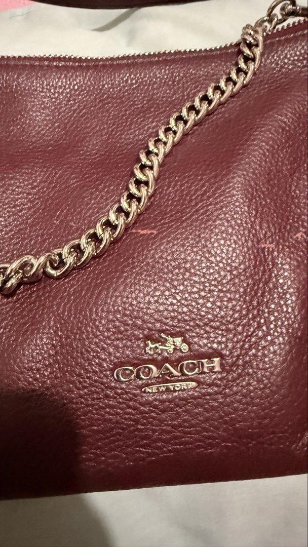 Coach Carrie Crossbody Clutch (Category: Luxury Bags & Wallets) located in Bacoor. Submitted by reich23 (Listing ID 1455462876, Image 3). Description: Crafted from durable pebbled leather in a rich burgundy/oxblood shade, featuring a silver-tone chain short handle, a raised Coach metallic logo, and a detachable longer leather strap for crossbody styling..