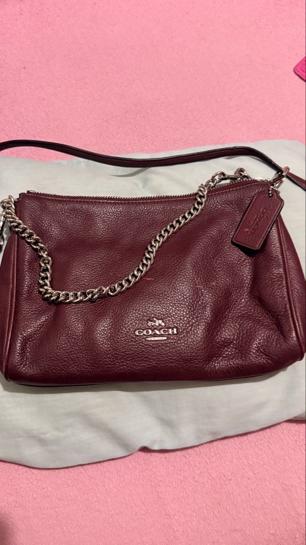Coach Carrie Crossbody Clutch (Category: Luxury Bags & Wallets) located in Bacoor. Submitted by reich23 (Listing ID 1455462876, Image 2). Description: Crafted from durable pebbled leather in a rich burgundy/oxblood shade, featuring a silver-tone chain short handle, a raised Coach metallic logo, and a detachable longer leather strap for crossbody styling..