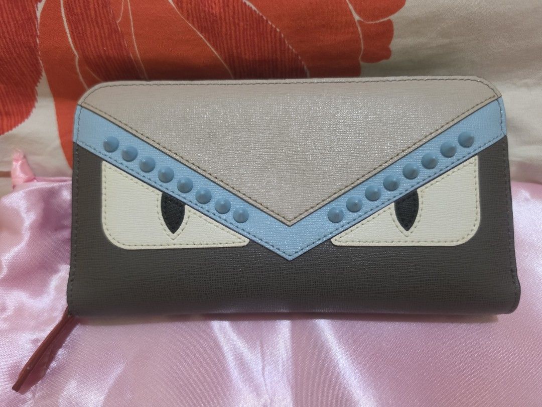 Fendi Monster Zip Around Wallet (Category: Luxury Bags & Wallets) located in Cavite. Submitted by kazi_preloved (Listing ID 1455368982, Image 1). Description: - 100% Authentic Fendi wallet in grey and beige. - Iconic Monster Eyes design with light blue studded accents. - Vibrant red interior. - Multiple card slots for organization. - Convenient zippered compartment. - with certificate of authenticity.