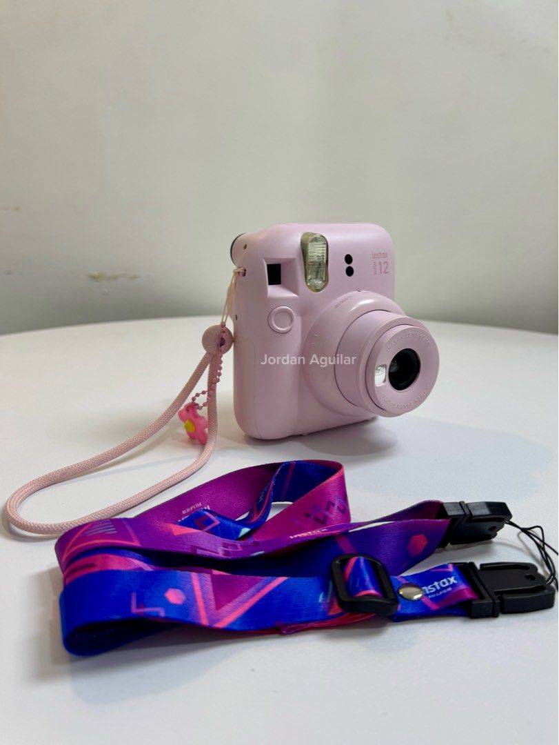 Fujifilm Instax Mini 12 Camera Bundle Pink (Category: Cameras) located in Manila. Submitted by jordanagui71577 (Listing ID 1455376176, Image 2). Description: - Pink Fujifilm Instax Mini 12 camera - Includes original box and manual - Comes with a clear protective case - Includes a blue Instax bag with pink and teal pouches - Two straps included: pink with flower and colorful patterned strap - Great for instant photos!.