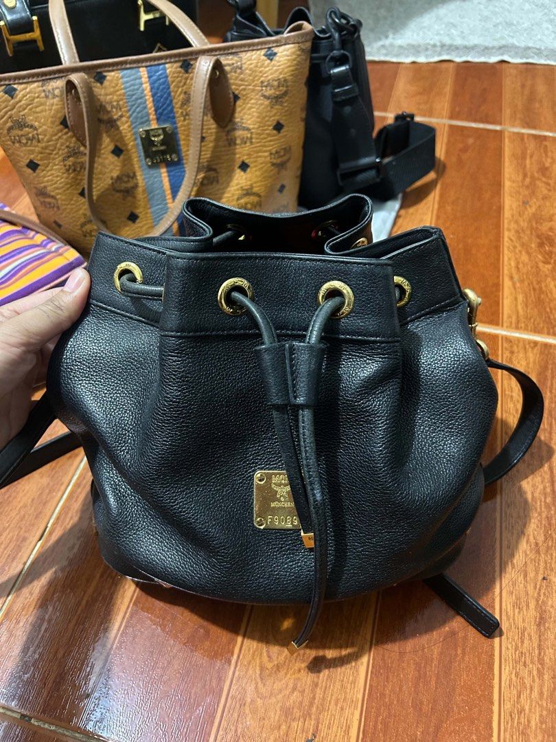 MCM Black Leather Bucket Bag (Category: Luxury Bags & Wallets) located in Caloocan City. Submitted by jill262626 (Listing ID 1455332734, Image 3). Description: - Authentic MCM bucket bag - Color: Black leather with gold hardware - Closure: Drawstring - Interior: Vibrant red lining - Strap: Detachable for versatile wear - Condition: Minor scuffs on the bottom, otherwise in good overall shape - Perfect for stylish everyday use.