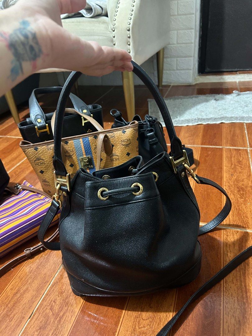 MCM Black Leather Bucket Bag (Category: Luxury Bags & Wallets) located in Caloocan City. Submitted by jill262626 (Listing ID 1455332734, Image 2). Description: - Authentic MCM bucket bag - Color: Black leather with gold hardware - Closure: Drawstring - Interior: Vibrant red lining - Strap: Detachable for versatile wear - Condition: Minor scuffs on the bottom, otherwise in good overall shape - Perfect for stylish everyday use.