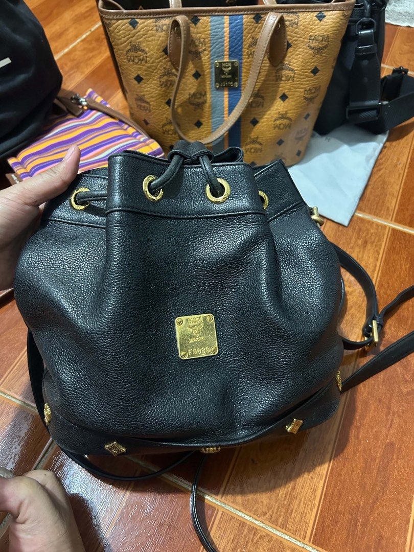 MCM Black Leather Bucket Bag (Category: Luxury Bags & Wallets) located in Caloocan City. Submitted by jill262626 (Listing ID 1455332734, Image 1). Description: - Authentic MCM bucket bag - Color: Black leather with gold hardware - Closure: Drawstring - Interior: Vibrant red lining - Strap: Detachable for versatile wear - Condition: Minor scuffs on the bottom, otherwise in good overall shape - Perfect for stylish everyday use.
