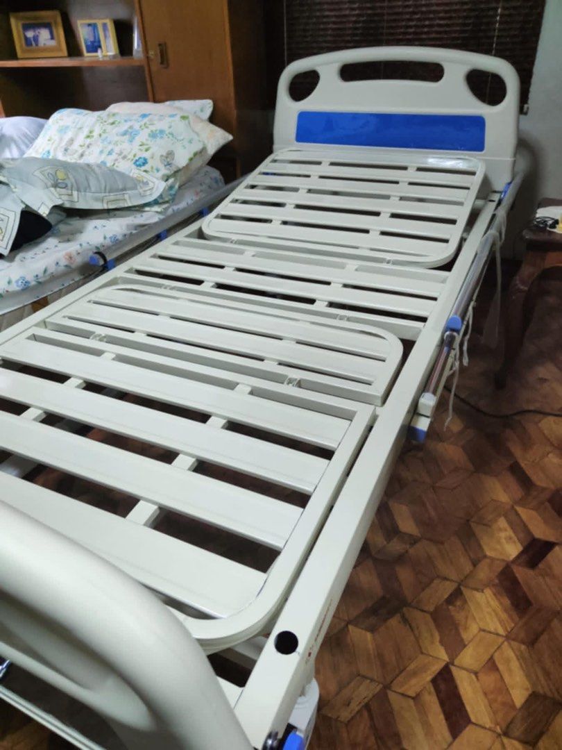 Surrmed Hospital Bed 2 Cranks (Category: Bed Frames & Mattresses) located in Alaminos. Submitted by irheaaa (Listing ID 1455349322, Image 2). Description: - Adjustable hospital bed - White and blue color scheme - Safety side rails included - Sturdy metal frame - Easy mobility with wheels - Comes with a blue mattress cover - Ideal for home care needs.