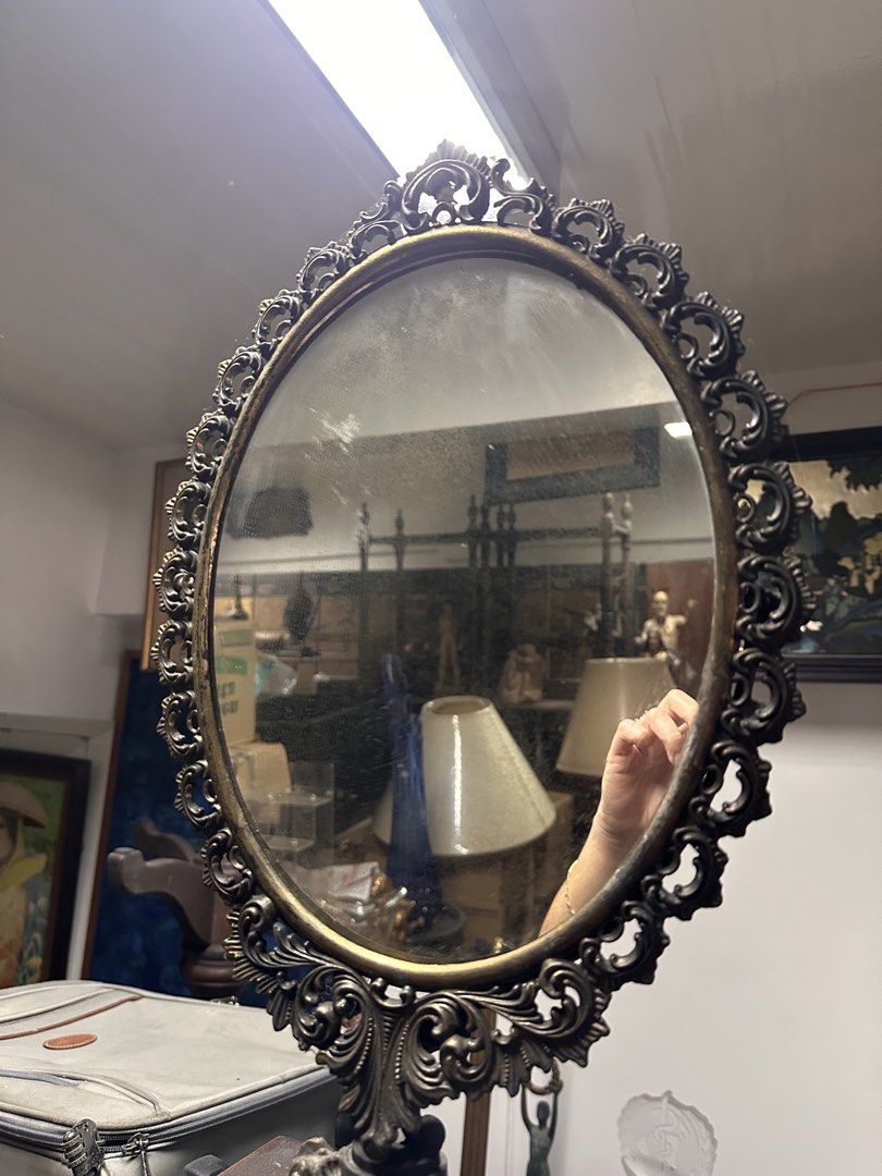Vintage Ornate Metal Tabletop Vanity Mirror (Category: Mirrors) located in Quezon City. Submitted by anjherga27 (Listing ID 1455372133, Image 2). Description: - Ornate metal tabletop mirror with a vintage feel - Oval shape with decorative scrollwork - Sturdy wooden base - Ideal for vanities, dressers, or any room needing a classic accent - Mirror surface has some dust and smudges (easily cleanable).
