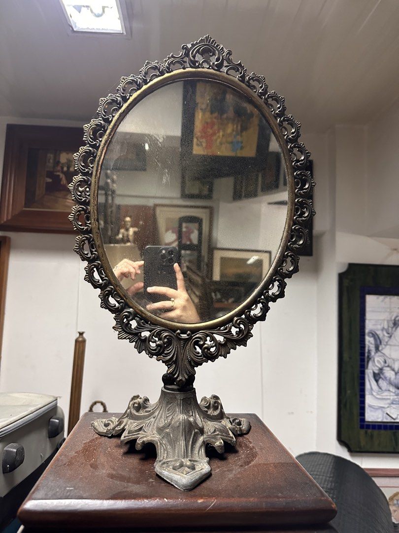Vintage Ornate Metal Tabletop Vanity Mirror (Category: Mirrors) located in Quezon City. Submitted by anjherga27 (Listing ID 1455372133, Image 1). Description: - Ornate metal tabletop mirror with a vintage feel - Oval shape with decorative scrollwork - Sturdy wooden base - Ideal for vanities, dressers, or any room needing a classic accent - Mirror surface has some dust and smudges (easily cleanable).