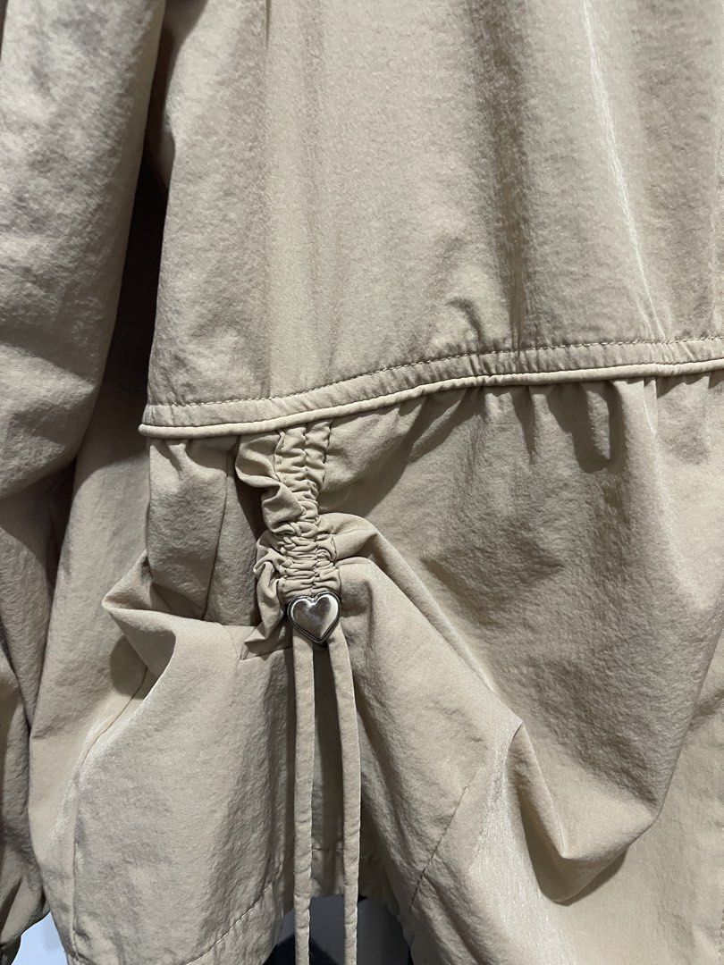Beige Drawstring Waist Jacket with Heart Charm (Category: Coats, Jackets and Outerwear) located in Manila. Submitted by ttbbkk (Listing ID 1455600859, Image 2). Description: - Lightweight beige jacket - Zip-up front with stand collar - Elasticated cuffs and hem - Adjustable drawstring waist with cute heart charms - Ideal for layering - Easy to style.