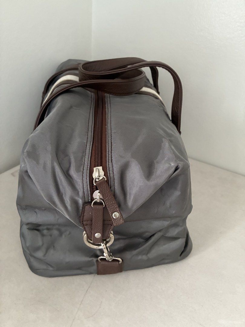 Grey Duffel Bag with Brown Leather Handles (Category: Luxury Bags & Wallets) located in Manila. Submitted by snappyaura (Listing ID 1455618674, Image 2). Description: - Stylish grey duffel bag with brown leather accents. - Features a distinctive white stripe down the middle. - Bright orange interior for easy visibility. - Includes a convenient zippered pocket inside. - Ideal for weekend getaways or gym sessions. - Comfortable handles for easy car