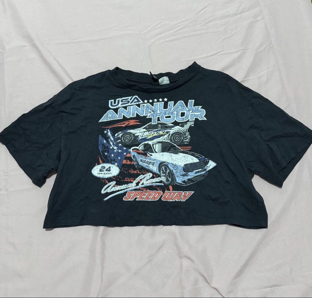 H&M dark blue Crop top (Category: Shirts) located in Muntinlupa City. Submitted by sunwonx (Listing ID 1455605709, Image 1). Description: - dark blue cropped t-shirt - Features 'USA Annual Tour' graphic with racing cars and American flag - Short sleeves - Relaxed fit - Ideal for a casual, edgy look - Pairs well with jeans or shorts.