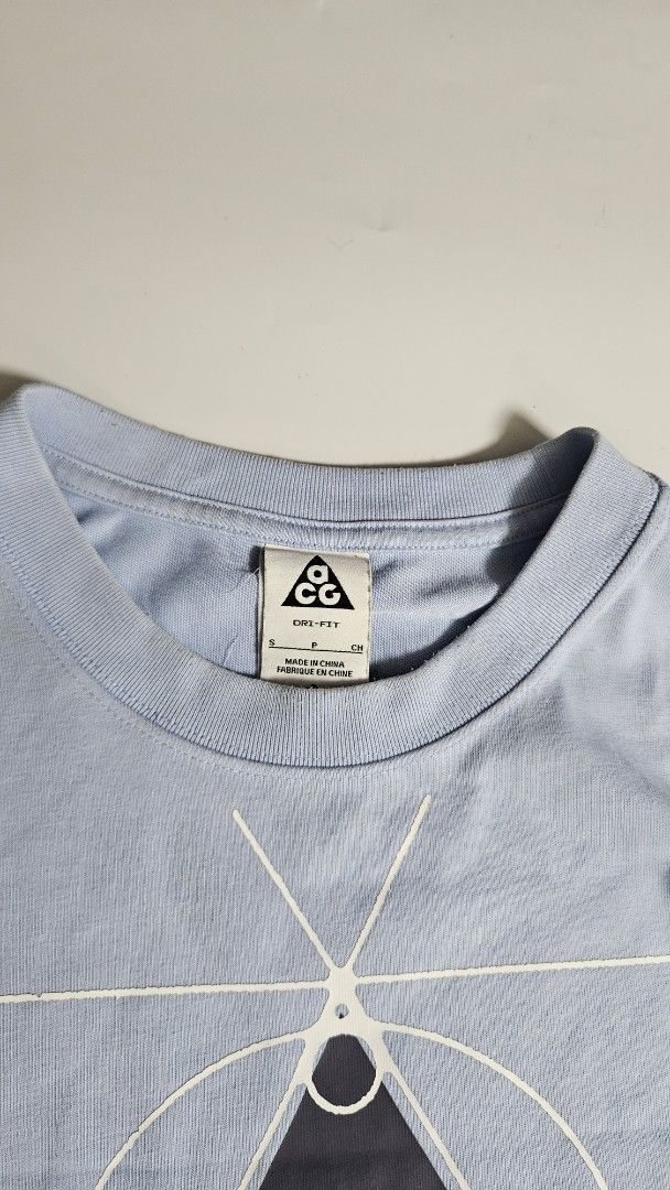 Nike ACG Leyline T-Shirt (Category: Tshirts & Polo Shirts ) located in Alfonso. Submitted by jbcamet (Listing ID 1455613264, Image 2). Description: - Light blue Nike ACG t-shirt - Features iconic ACG triangle logo graphic - Made with Dri-FIT material for comfort - Size S - Ideal for everyday wear or outdoor activities.