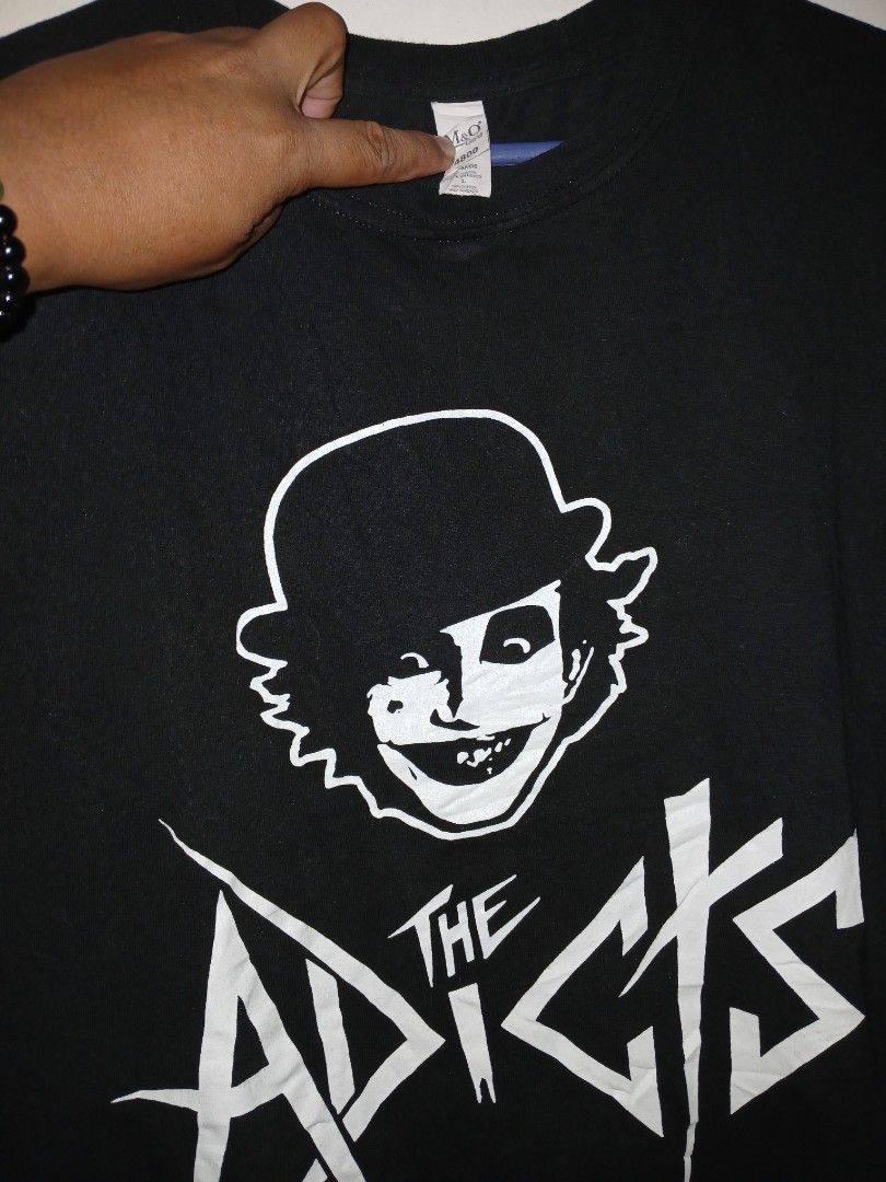 The Adicts Skull T-Shirt (Category: Tshirts & Polo Shirts ) located in Manila. Submitted by ninshok (Listing ID 1455627790, Image 2). Description: - Black t-shirt - Features The Adicts graphic print - Includes skull design and band logo - Small tear on the hem (visible in the last photo) - Perfect for fans of The Adicts.
