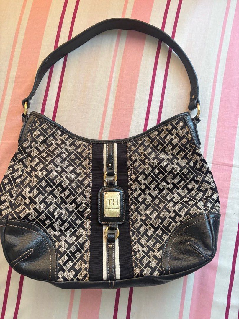 Tommy Hilfiger Monogram Shoulder Bag (Category: Luxury Bags & Wallets) located in Manila. Submitted by kzcat (Listing ID 1455527084, Image 1). Description: - Authentic Tommy Hilfiger shoulder bag - Classic TH monogram pattern in black and tan - Genuine leather trim and strap - Interior zippered pocket for essentials - Elegant gold hardware details - Iconic red Tommy Hilfiger interior tag It's been used! It has scratches on the front brand gold ha