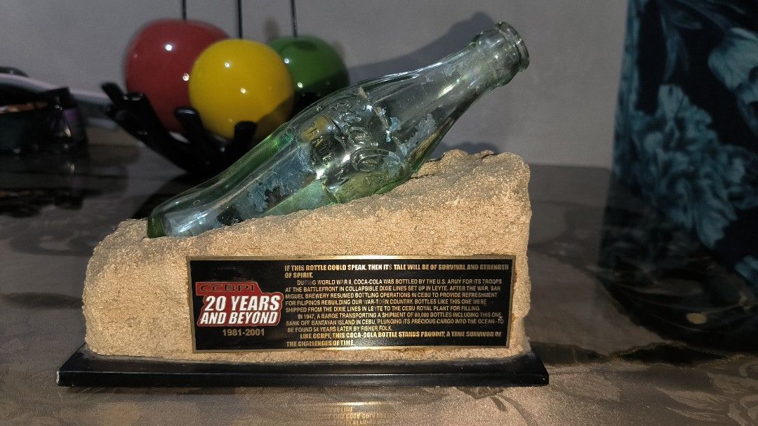 CCBPI 20 Years and Beyond 2001 (Category: Vintage Collectibles) located in Bulacan. Submitted by tripledouble532 (Listing ID 1455745343, Image 1). Description: Coca-Cola Philippines CCBPI 20 Years and Beyond 2001 Beach Sand Base w/ Bottle. Now 45 years and counting. Plaque says that during World War II, Coca-Cola was bottled for U.S. Army troops in Cebu. The bottle is a genuine glass Coca-Cola contour bottle, and the markings visible on the front