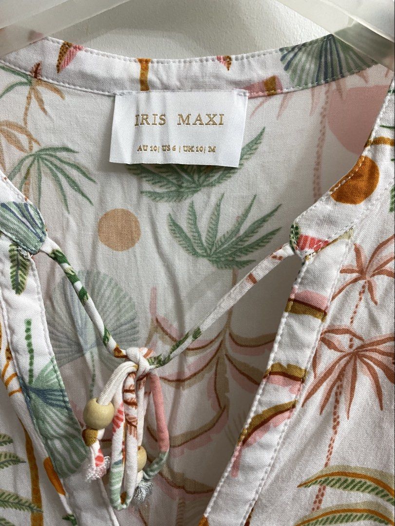 IRIS MAXI White Tropical Print Tiered Button-Up Dress (Category: Dresses) located in Quezon City. Submitted by thebutingthings (Listing ID 1455792123, Image 2). Description: - White dress with a vibrant tropical palm tree print - Tiered skirt for a flowy silhouette - Button-up front for adjustable styling - Flattering V-neck with a cute tie detail and wooden beads - Stylish puff sleeves with tie cuffs - Made from lightweight fabric, ideal for hot