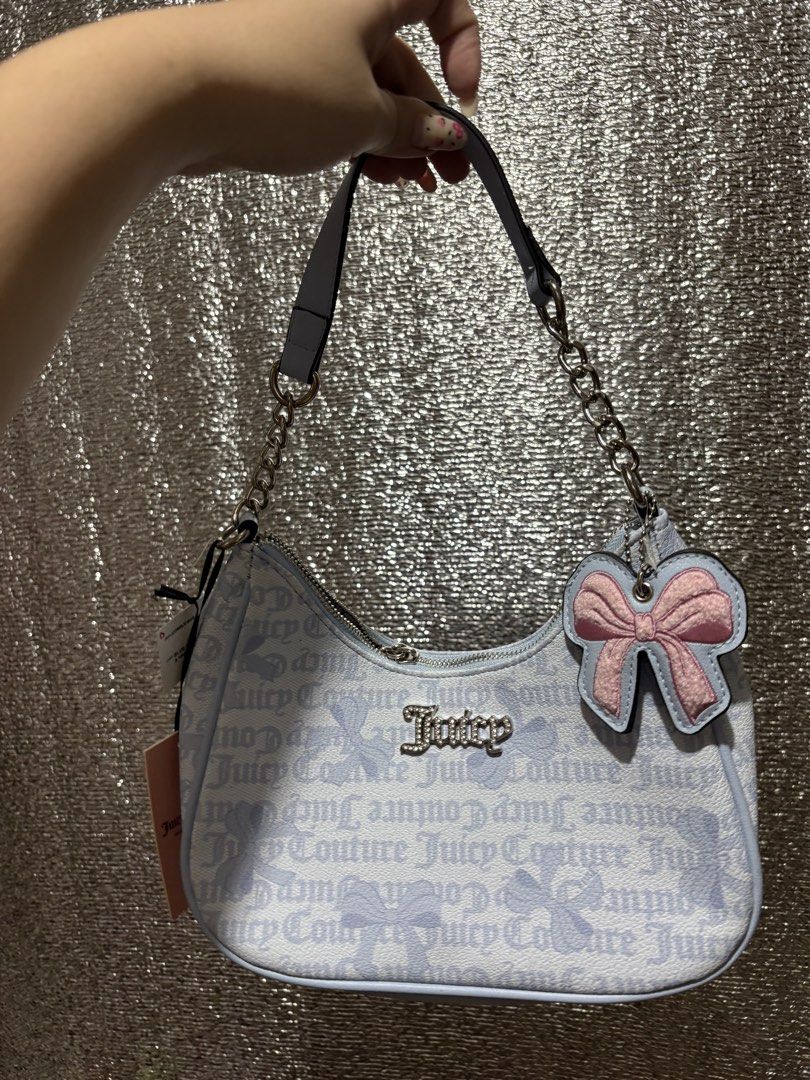 Juicy Couture Blue Monogram Shoulder Bag with Bow Charm (Category: Shoulder Bags) located in Imus. Submitted by imaubleee16 (Listing ID 1455810796, Image 1). Description: - Cute Juicy Couture shoulder bag - All-over light blue and white monogram print - Adorable pink bow charm attached - Stylish silver chain strap - Secure zipper closure - Versatile for everyday or evening wear.
