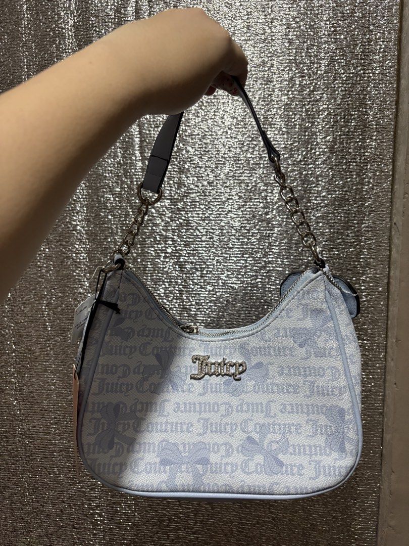 Juicy Couture Blue Monogram Shoulder Bag with Bow Charm (Category: Shoulder Bags) located in Imus. Submitted by imaubleee16 (Listing ID 1455810796, Image 2). Description: - Cute Juicy Couture shoulder bag - All-over light blue and white monogram print - Adorable pink bow charm attached - Stylish silver chain strap - Secure zipper closure - Versatile for everyday or evening wear.