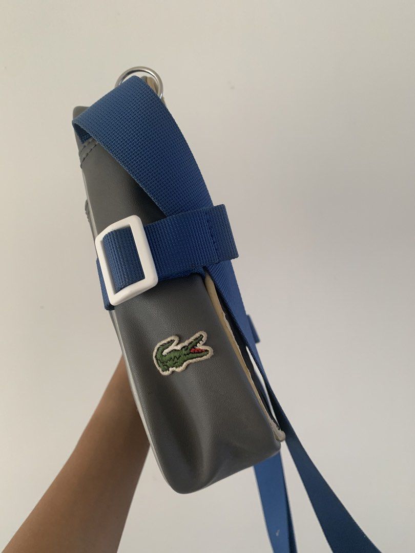 Lacoste Grey Crossbody Bag with Blue Strap (Category: Cross-body Bags) located in San Luis. Submitted by dialopez (Listing ID 1455748531, Image 3). Description: - Grey Lacoste crossbody bag - Blue adjustable strap - Front pocket with black textured panel - Main compartment with internal pockets - Small Lacoste crocodile logo on the side - Ideal for everyday use.