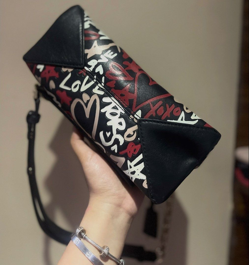 Michael Kors Graffiti Print Leather Shoulder Bag (Category: Luxury Bags & Wallets) located in Trece Martires City. Submitted by justprelovedx (Listing ID 1455697235, Image 2). Description: - Authentic Michael Kors bag - Unique graffiti print design - Black leather with vibrant red, white, and pink accents - Luxurious gold chain strap and hardware - Secure and stylish turn-lock closure - Perfect for adding a statement piece to your look.