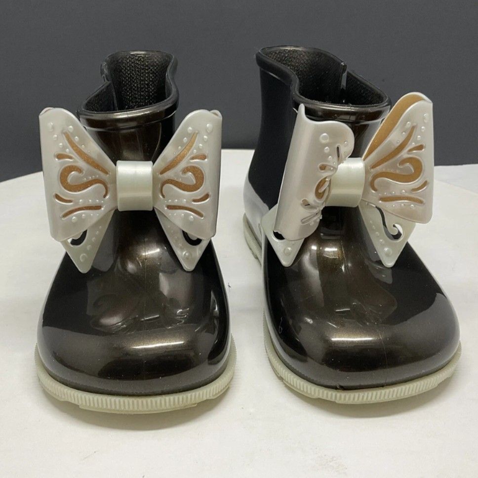 Mini Melissa Sugar Rain Bow Booties Black US7 (Category: Babies & Kids Fashion) located in Manila. Submitted by gigisimeon (Listing ID 1455769915, Image 1). Description: Mini Melissa Sugar Rain Bow Booties Black USA 7 *Used 2-3 x ONLY (church/mall) *with box -Cute Mini Melissa rain boots for kids. - Shiny dark brown/black color. - Features a pretty white and gold bow on the front. - Easy slip-on design. - Ideal for rainy days or outdoor play. - '