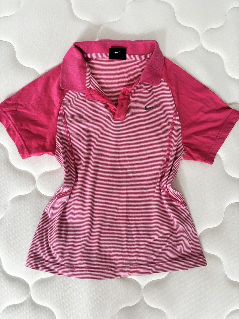 Nike Pink Striped Polo Shirt (Category: Activewear) located in Binan City. Submitted by byhiraeth (Listing ID 1455791936, Image 1). Description: - Pink and white striped Nike polo shirt - Solid pink shoulders and collar - Short sleeves - Button-up neckline - Small Nike swoosh logo on chest - Ideal for sports or casual wear - Comfortable and breathable fabric.