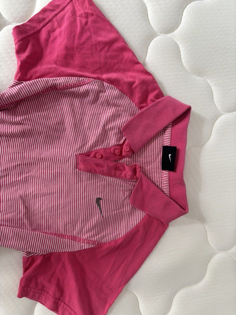 Nike Pink Striped Polo Shirt (Category: Activewear) located in Binan City. Submitted by byhiraeth (Listing ID 1455791936, Image 3). Description: - Pink and white striped Nike polo shirt - Solid pink shoulders and collar - Short sleeves - Button-up neckline - Small Nike swoosh logo on chest - Ideal for sports or casual wear - Comfortable and breathable fabric.