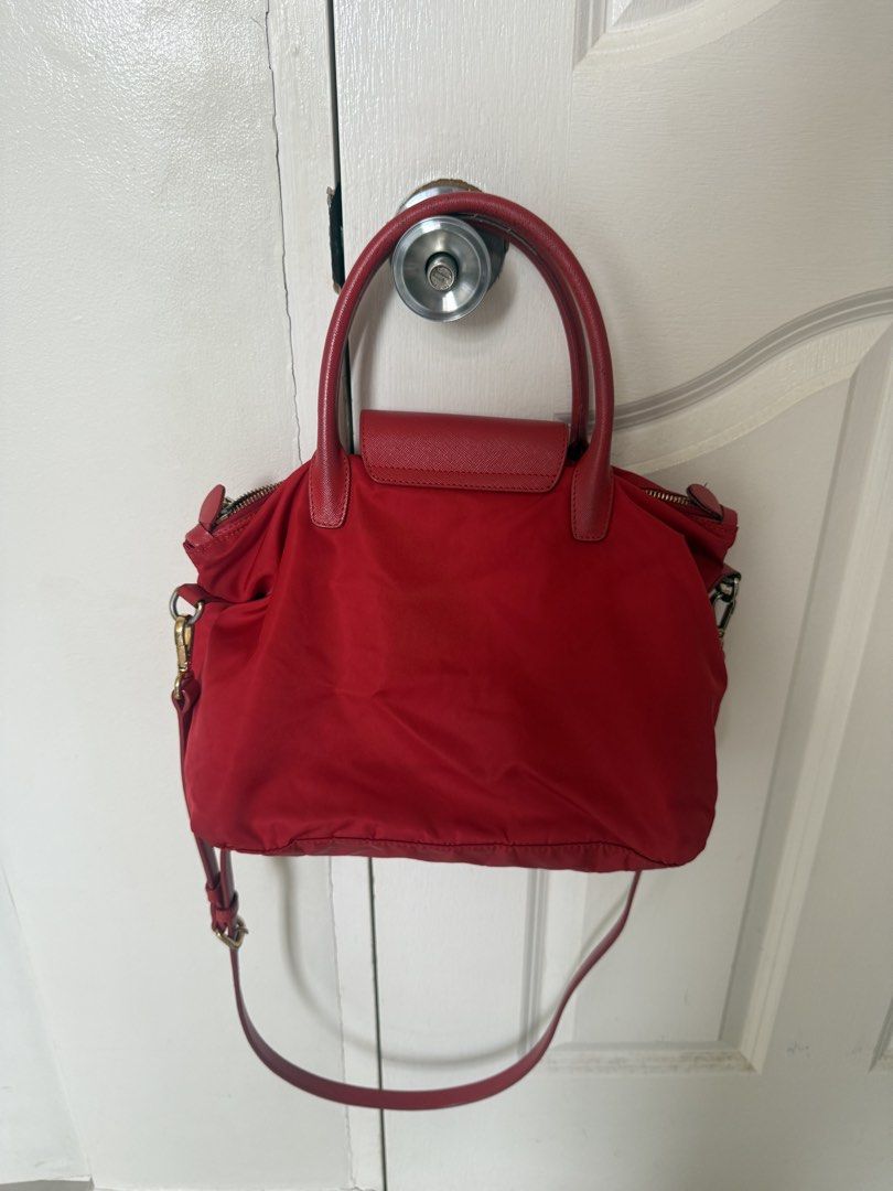 Prada Red Nylon Leather Trim Top Handle Bag (Category: Luxury Bags & Wallets) located in Muntinlupa City. Submitted by joycups (Listing ID 1455811459, Image 2). Description: - Authentic Red Prada Bag - Durable Nylon Body with Leather Trim - Comfortable Leather Handles - Detachable Shoulder Strap for Versatility - Secure Zipper Closure on Top - Convenient Front Flap Pocket with Magnetic Snap - Elegant Gold Hardware Details - Ideal Everyday Bag.