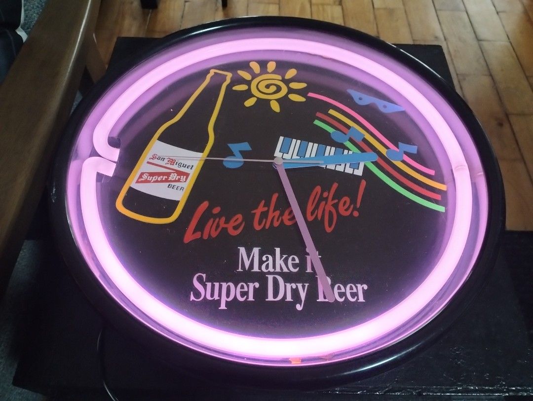 San Miguel Super Dry Beer Neon Clock (Category: Clocks) located in Cainta. Submitted by vacg0630 (Listing ID 1455788323, Image 3). Description: - Vintage San Miguel Super Dry Beer neon clock - Vibrant pink neon light - Unique design featuring a beer bottle, sun, piano keys, and musical notes - Text includes 'Live the life!' and 'Make it Super Dry Beer' - Powered by reliable quartz movement Clock not WORKING 4800 Shipping not ncluded QR code/Bank 