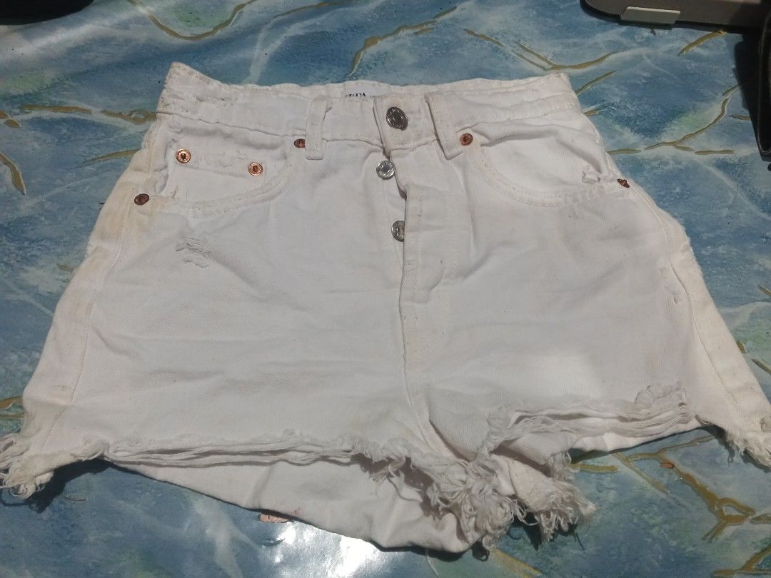 Zara White Denim Ripped Shorts (Category: Shorts) located in Manila. Submitted by icamalicdem29 (Listing ID 1455852954, Image 3). Description: - Zara white denim shorts - Button fly closure - Distressed hem with frayed edges - Minor marks on front (please check photos) - Waist measures approximately 13 inches across.