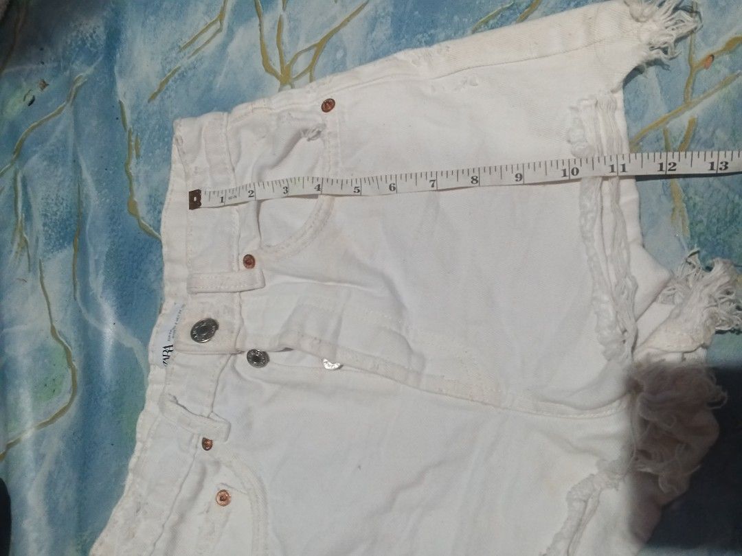 Zara White Denim Ripped Shorts (Category: Shorts) located in Manila. Submitted by icamalicdem29 (Listing ID 1455852954, Image 2). Description: - Zara white denim shorts - Button fly closure - Distressed hem with frayed edges - Minor marks on front (please check photos) - Waist measures approximately 13 inches across.