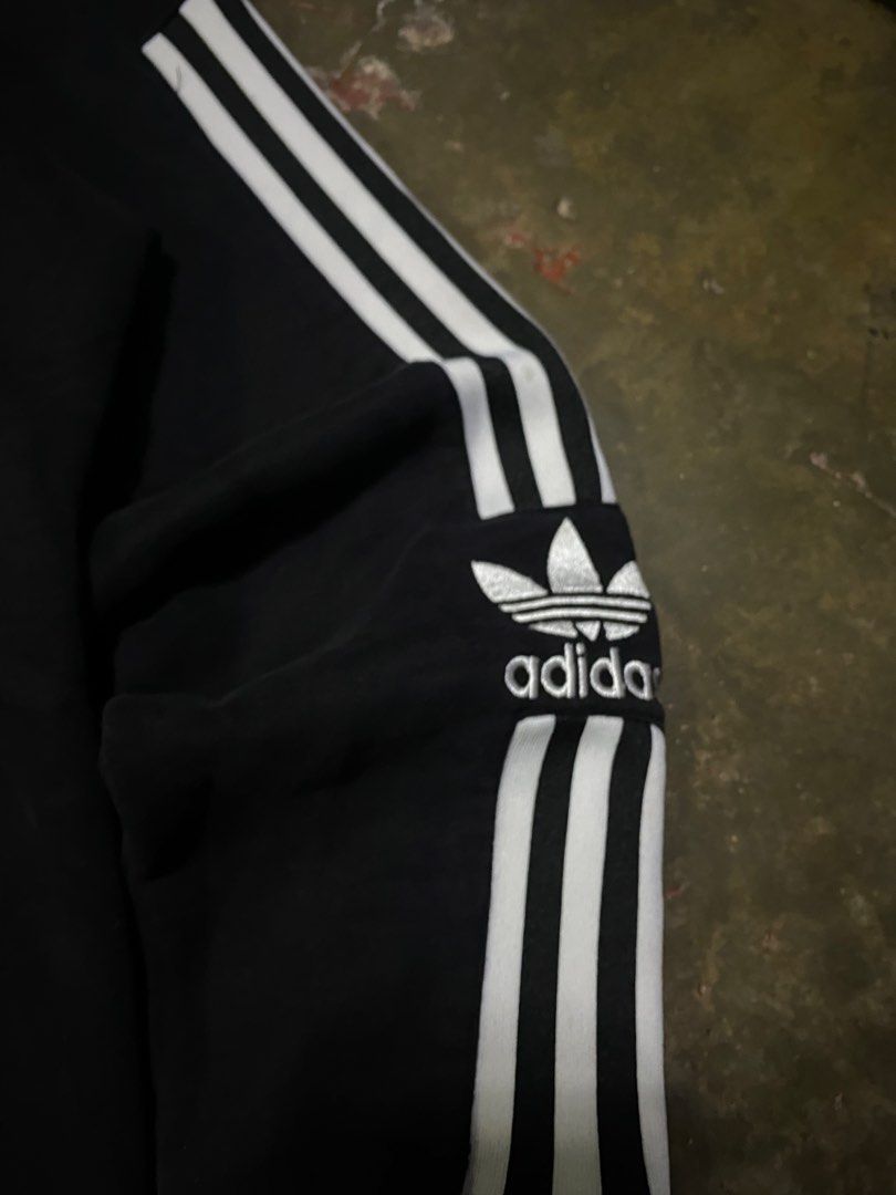 Adidas Black Sweatshirt with White Stripes (Category: Coats, Jackets and Outerwear) located in Malabon City. Submitted by yivsthrift (Listing ID 1455996337, Image 3). Description: - Classic black Adidas sweatshirt - Features iconic white three stripes on sleeves - Embroidered Adidas trefoil logo on chest - Approximate measurements: 27" length x 20.5" width - Ideal for everyday casual wear.