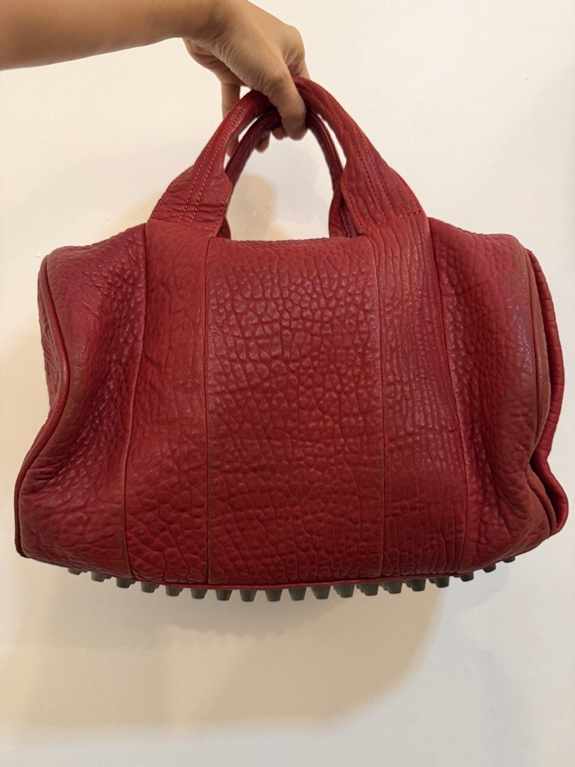 Alexander Wang Rocco Duffle bag (Category: Luxury Bags & Wallets) located in Santa Maria. Submitted by baghoarder23 (Listing ID 1455929657, Image 1). Description: - Classic red leather satchel bag - Signature stud detailing on bottom and sides - Versatile carrying options: top handles and detachable shoulder strap - Spacious interior for all your essentials - A chic and timeless designer accessory.