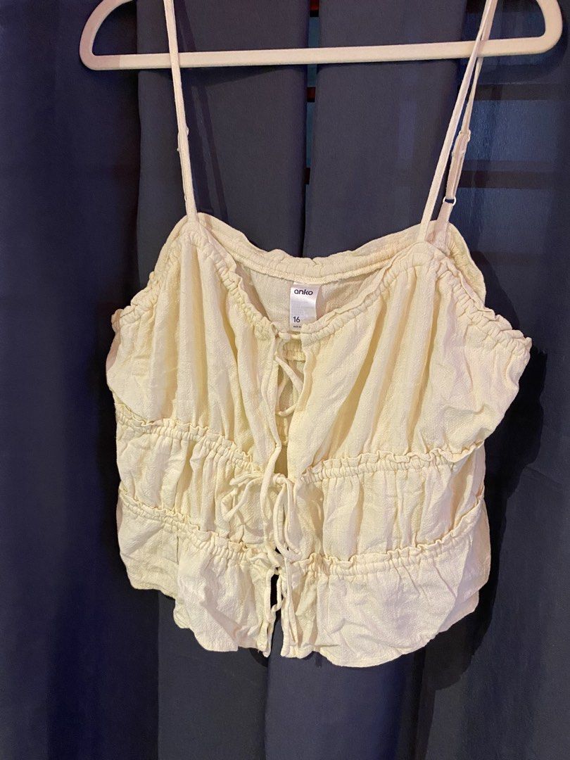 Anko Cream Tie Front Ruffle Crop Top size M-L (Category: Blouses) located in Manila. Submitted by annamacuto (Listing ID 1456007725, Image 1). Description: - Cream-colored crop top from Anko - Size 16 - Features a cute tie-front design - Ruffled details along the hem and bust - Adjustable spaghetti straps - Ideal for a summery and stylish look.