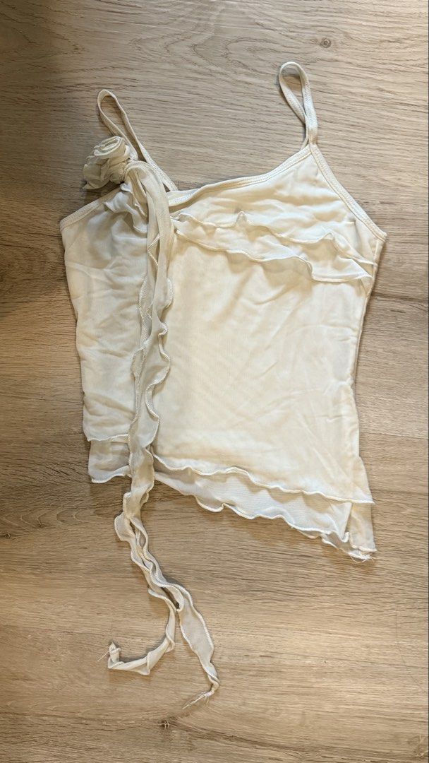Cream Ruffle Mesh Cami Top with Flower Detail (Category: Sleeveless) located in Makati City. Submitted by sophia.lp (Listing ID 1455893135, Image 1). Description: shipping c/o buyer - Cream cami top - Delicate mesh overlay - Ruffled neckline and hem - Cute flower detail on strap - Side tie has slight fraying - Ideal for layering or wearing solo.