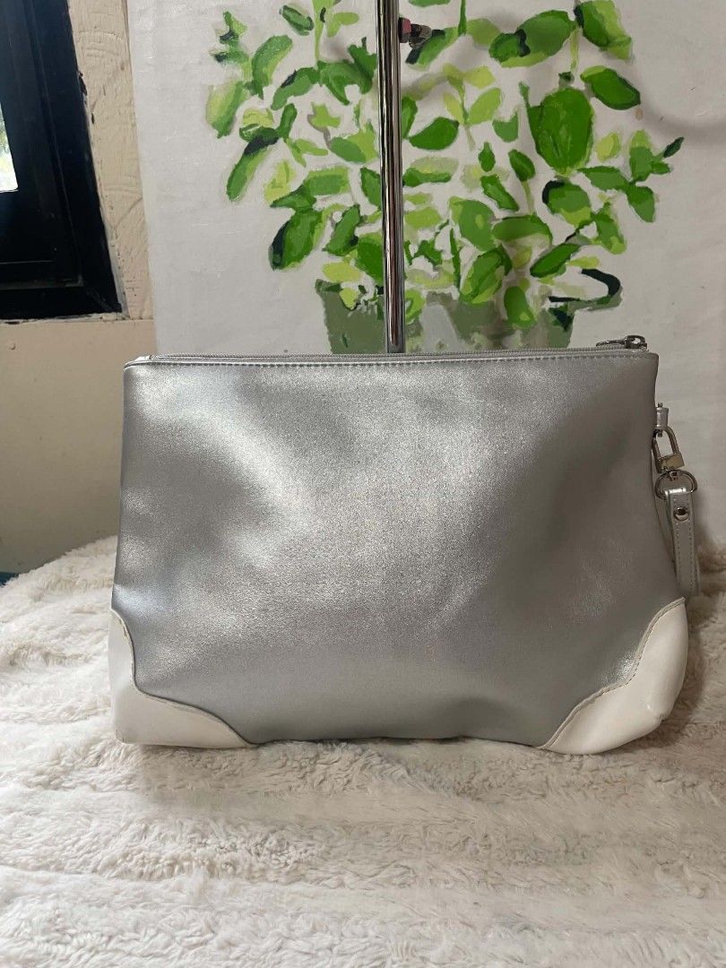 Fantom Silver Heart Logo Clutch Bag (Category: Clutches) located in Naawan. Submitted by twilly.apparel2 (Listing ID 1455862709, Image 2). Description: - issue may bakbak sa white color Chic silver clutch bag with elegant white accents. - Features a prominent embossed heart logo on the front with 'FANOLL' branding. - Comes with a convenient wrist strap for easy carrying. - Zipper closure ensures your essentials are secure. - Please note: Minor we
