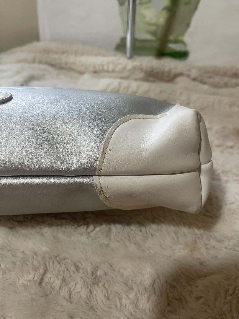 Fantom Silver Heart Logo Clutch Bag (Category: Clutches) located in Naawan. Submitted by twilly.apparel2 (Listing ID 1455862709, Image 3). Description: - issue may bakbak sa white color Chic silver clutch bag with elegant white accents. - Features a prominent embossed heart logo on the front with 'FANOLL' branding. - Comes with a convenient wrist strap for easy carrying. - Zipper closure ensures your essentials are secure. - Please note: Minor we