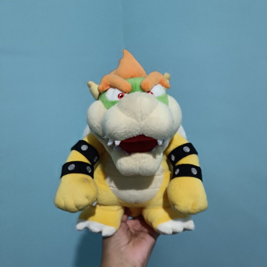Nintendo Super Mario Bowser Plush Toy (Category: Plushies & Soft Toys) located in Baguio. Submitted by baileybails (Listing ID 1456051828, Image 1). Description: - Bowser plush toy from the Super Mario franchise. - Classic design with a yellow body, green shell, and orange spikes. - Detailed with black studded armbands. - Shows some wear on the horn, as visible in the pictures. - An ideal collectible for any Super Mario enthusiast..