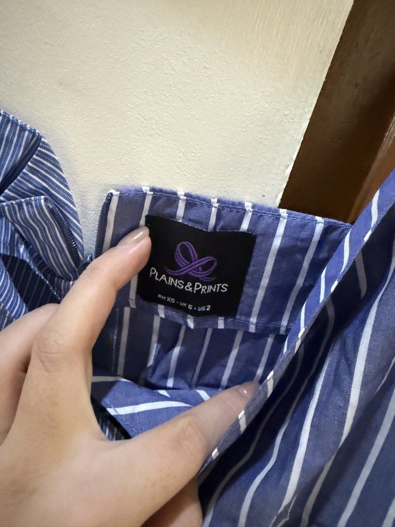 Plains & Prints Blue Striped Peplum Wrap Top (Category: Blouses) located in Cavite. Submitted by katsibulo (Listing ID 1455966679, Image 2). Description: - Cute blue and white striped peplum top - Brand: Plains & Prints - Style: Wrap with V-neckline - Features: Adjustable spaghetti straps, flattering peplum hem - Versatile: Perfect for dressing up or down, pairs well with jeans or skirts.
