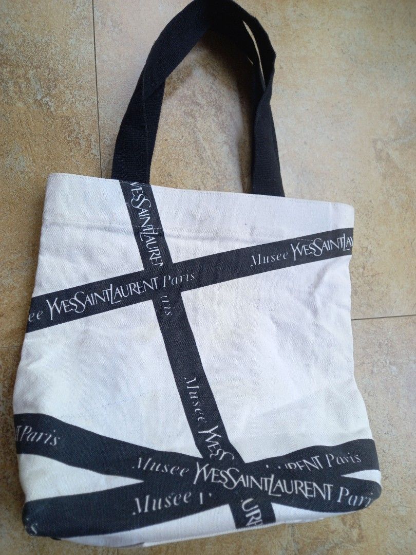 Yves Saint Laurent Musee Tote Bag (Category: Luxury Bags & Wallets) located in Davao. Submitted by kirk214red-50020 (Listing ID 1455891985, Image 1). Description: - White canvas tote bag - Black Yves Saint Laurent ribbon detail - Magnetic snap closure - Interior zippered pocket - Perfect for everyday use or travel.