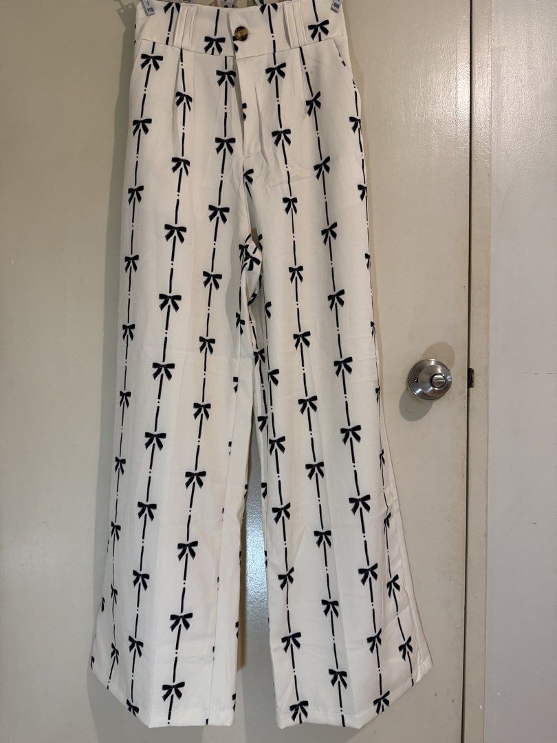 BKK Finds: Wisdom Studio Ribbon Printed Co-Ord Set (Category: Sets or Coordinates) located in Mandaluyong City. Submitted by anne_manda (Listing ID 1456079474, Image 3). Description: **Worn only once** Features an off-white/cream base adorned with a dainty black bow and pinstripe print. The vest has a flattering V-neck cut with tortoiseshell button details, while the high-waisted wide-leg trousers offer a sleek, elongated silhouette with a comfor