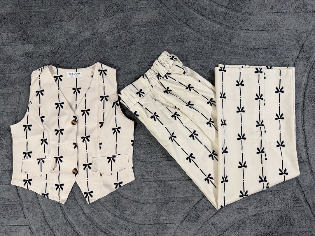 BKK Finds: Wisdom Studio Ribbon Printed Co-Ord Set (Category: Sets or Coordinates) located in Mandaluyong City. Submitted by anne_manda (Listing ID 1456079474, Image 1). Description: **Worn only once** Features an off-white/cream base adorned with a dainty black bow and pinstripe print. The vest has a flattering V-neck cut with tortoiseshell button details, while the high-waisted wide-leg trousers offer a sleek, elongated silhouette with a comfor