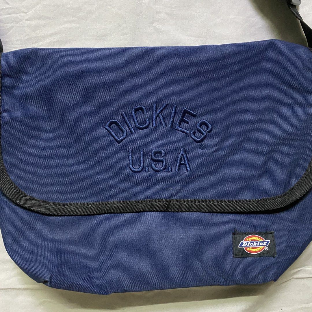 Dickies USA Navy Blue Messenger Bag (Category: Sling Bags) located in Marikina City. Submitted by beeeekenneth (Listing ID 1456138379, Image 2). Description: - Navy blue Dickies messenger bag - Embroidered 'Dickies USA' logo on front flap - Small Dickies logo patch on front - Zippered pocket on the back - Snap button closure for main compartment - Adjustable strap for comfortable wear - Ideal for everyday use Location: Marikina + we can do Lalamo