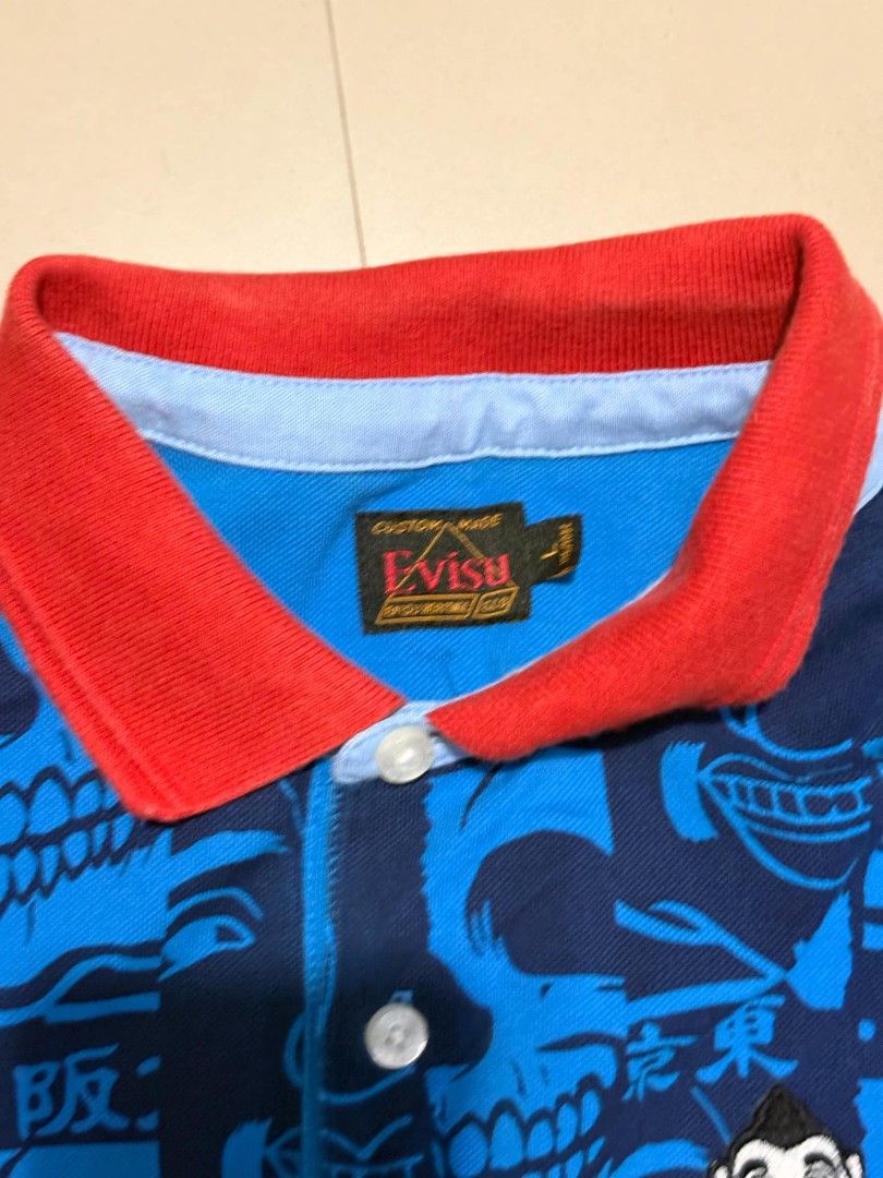 Evisu Custom Made Polo Shirt (Category: Tshirts & Polo Shirts ) located in Castillejos. Submitted by fnds_wr (Listing ID 1456192800, Image 2). Description: - Blue Evisu polo shirt - Unique all-over print featuring skulls and Japanese characters - Contrasting red collar detail - Short sleeves - Button-up front - Ideal for casual outfits.
