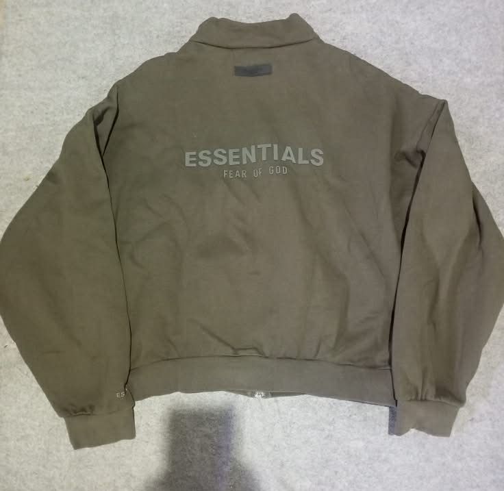 Fear of God Essentials Track Jacket (Category: Coats, Jackets and Outerwear) located in Lapu Lapu. Submitted by mysticwhale.cdda54 (Listing ID 1456175304, Image 2). Description: - Olive green track jacket from Essentials - Full zip closure with stand-up collar - Ribbed cuffs and hem for a snug fit - "ESSENTIALS FEAR OF GOD" logo prominently displayed on the back - Comfortable and stylish, ideal for layering.