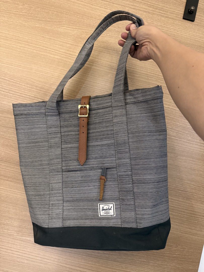 Grey Tote Bag (Category: Tote Bags) located in Taguig. Submitted by _philip_v_ (Listing ID 1456057767, Image 1). Description: Herschel Supply Co. Grey Tote Bag with Leather Accents Original Herschel tote bag. Grey color with leather enclosure. Has brown leather strap details and buckle closure. Front pocket with leather pull tab. Durable fabric with a darker base. Great for everyday use. Plenty of space inside. Clean interiors. I bought this in S